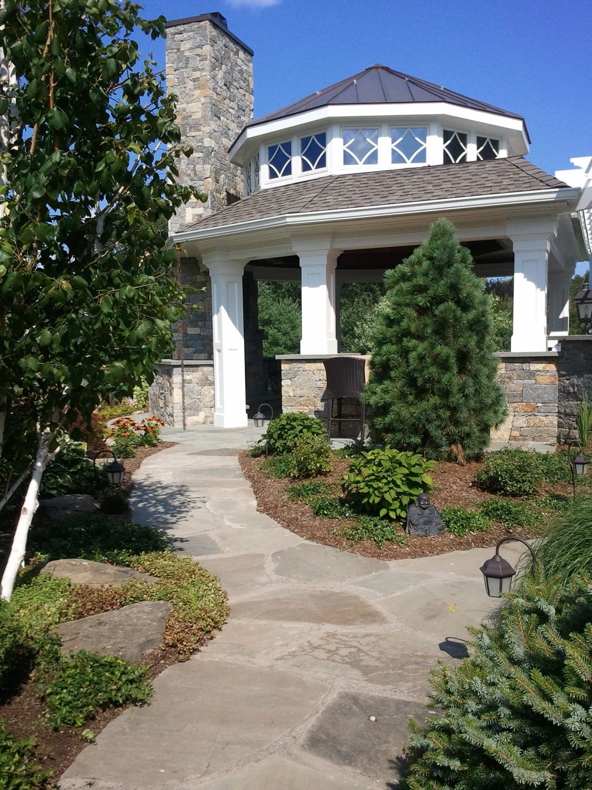 Irregular bluestone flagstone path leading to a copper-roofed stone pavilion