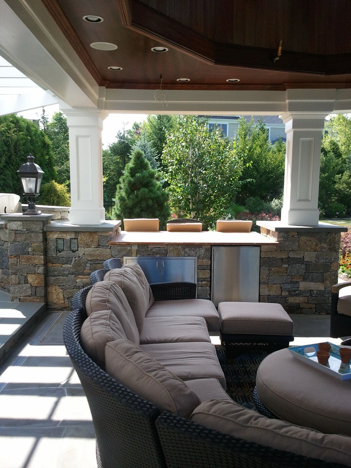 Inside a covered stone pavilion with a built-in stone bar and wicker lounge seating